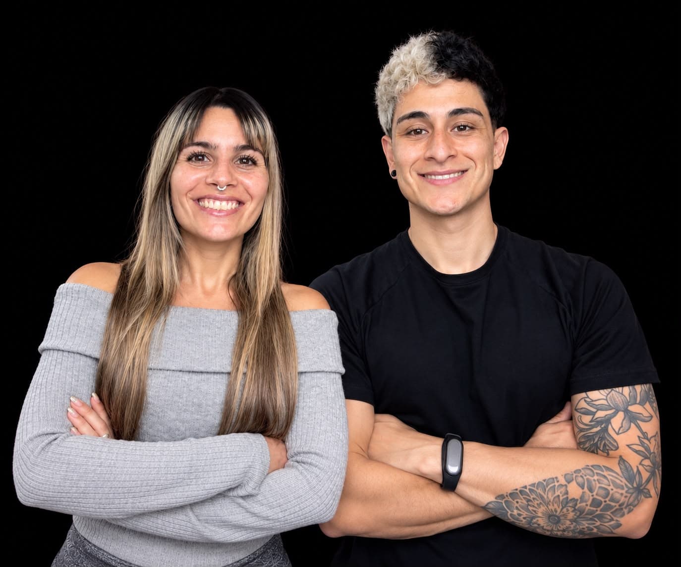 Alex Morales y Romi sonriendo con los brazos cruzados sobre fondo negro.